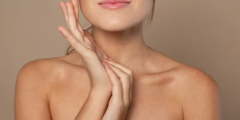 Qué son los exosomas y para qué sirven en la piel Mujer tocándose el cuello y el mentón, con la piel luminosa e hidratada, para ilustrar qué son los exosomas en la piel