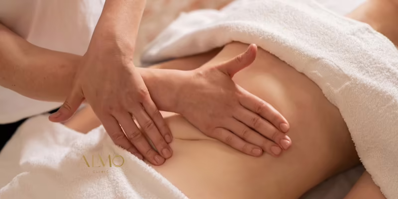Lymphatic massage after lipo: when to start and how many sessions Lymphatic massage on the abdomen: a therapist's hands moving with light pressure beside a towel