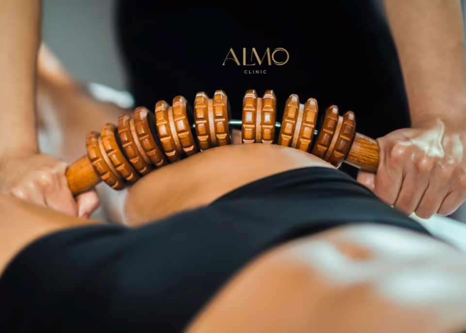 Maderoterapia abdominal y de cintura con rodillo de madera Terapeuta pasando un rodillo de madera por la cintura y la zona lumbar en una sesión de maderoterapia